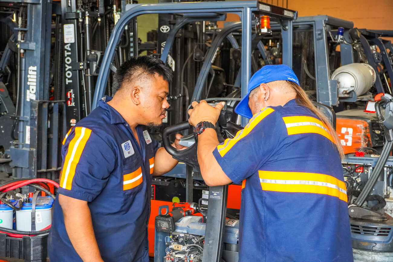 Our servicemen fixing a used forklift for improved performance.